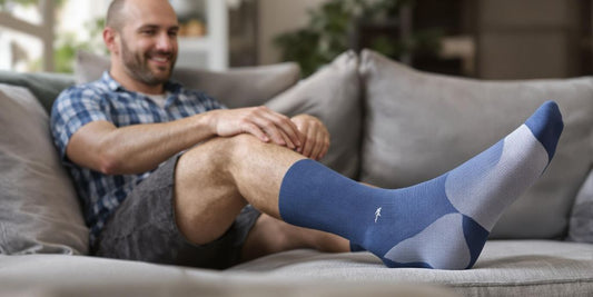 Man wearing support socks relaxing on a sofa.