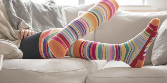 Person wearing large colorful compression socks relaxing at home