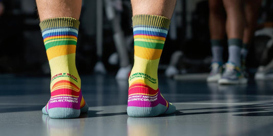 Athletic feet wearing colorful pressure socks on gym floor.