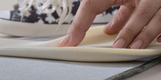 Hand pressing memory foam insole next to sneakers