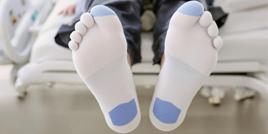 Close-up of feet in non-slip hospital socks on bed.