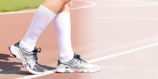 Person wearing white compression socks on outdoor running track