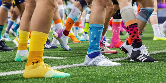 Athletes running on turf wearing colorful athletic socks