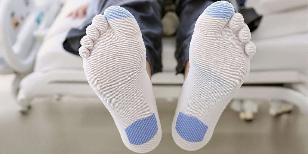 Close-up of feet in non-slip hospital socks on bed.