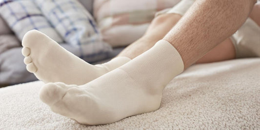 Man’s feet in cushioned diabetic socks on soft surface.
