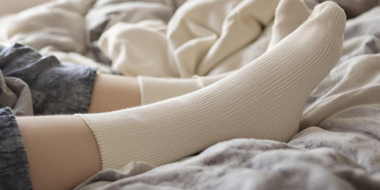 Soft socks on swollen feet resting on bed